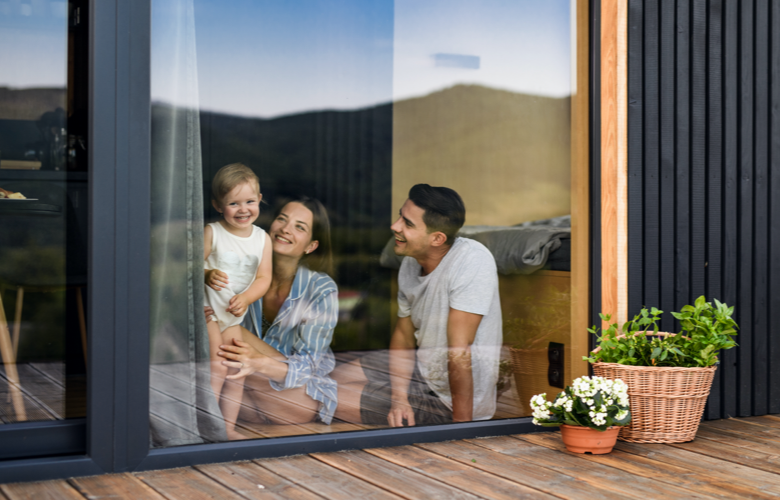 Haus finanzieren: Mann, Frau und deren Kind sitzen am Fenster und schauen raus